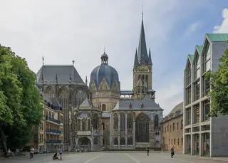 Aachen Cathedral’s dome, tall spire and Gothic choir rise beyond an open cobbled square.