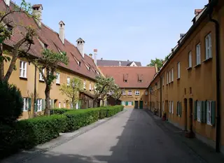 Ochre houses with red tiled roofs, green shutters and low hedges line a narrow lane.