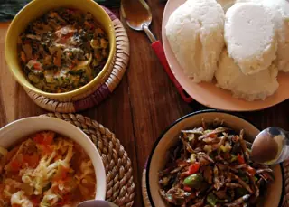 National food illustration of nshima and three relishes on ordinary plates and bowls; capture location unspecified.