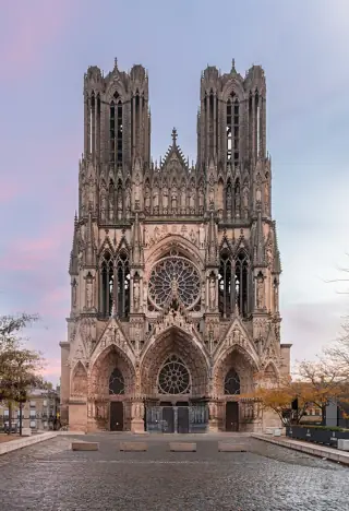 Twin Gothic towers rise above three carved portals and a cobbled forecourt.