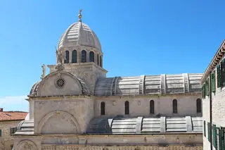 A stone cathedral dome and vaulted roofs against blue sky, with the lower church outside the source frame.