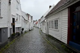 White timber houses line a wet cobbled street beneath a pale sky.