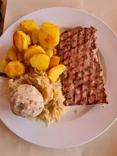 Regional illustration from Ville di Fiemme: dumpling, sauerkraut, grilled sausage and potatoes on a plain white plate.