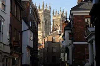 Gothic cathedral towers rise above a narrow shopping street.