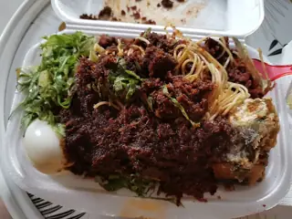 A takeaway meal topped with leafy greens, noodles, a boiled egg and dark sauce.