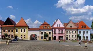 A row of pastel facades with varied gables faces a broad cobbled square.