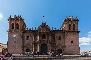 The cathedral’s broad carved stone facade and two square towers rise above visitors along the plaza.