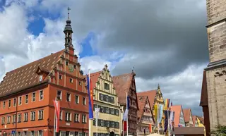 Orange, pale-green and half-timbered facades line a street beneath dramatic clouds.