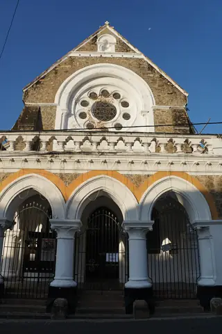 Three pointed entrance arches below a geometric rose window and stone gable at All Saints’ Church.