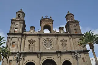 Two cathedral towers frame a central stone arch and circular window above partially visible entrance arches.