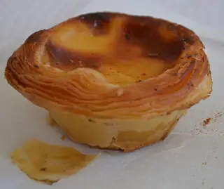 Golden flaky custard tart on a white paper napkin.