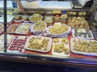 A glass counter filled with tortellini, tortelloni, tagliatelle and other fresh pasta, with dated price labels.