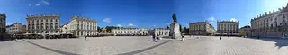 Very wide sunny panorama across Place Stanislas, its classical facades, central statue and scattered walkers.