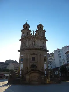 Twin towers and a curved stone church facade rising behind steps and a central fountain.