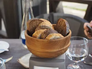 Slices of white and dark bread fill a wooden bowl on a restaurant table.