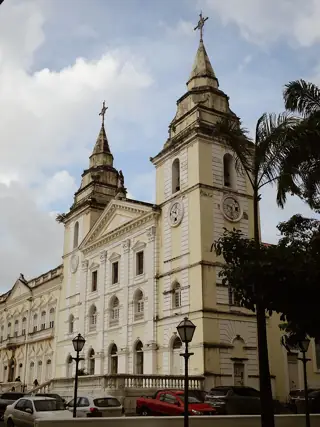 Angled view of the cathedral’s pale facade and twin towers above parked cars.