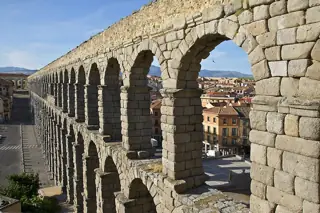 Two tiers of stone arches recede across the city beneath a blue sky.