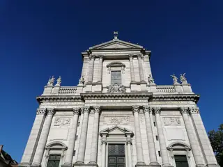 An upward view of the pale sculpted cathedral facade against deep blue sky.
