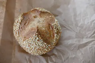 German bakery illustration photographed in Bavaria: a sesame-topped bread roll on plain brown paper.